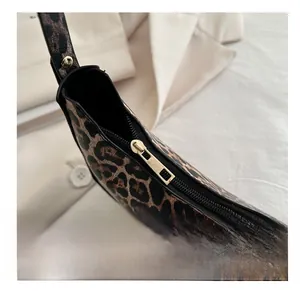 Détail de la fermeture éclair dorée et du tissu imprimé léopard du sac porté épaule