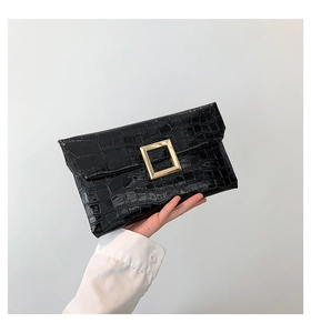 Detail of black faux crocodile skin envelope clutch bag with gold square buckle