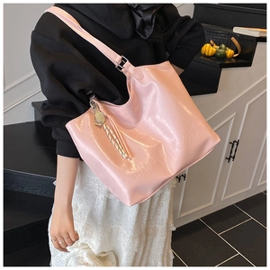 Pink patent leather tote bag with embossed lettering shown in a stylish indoor setting