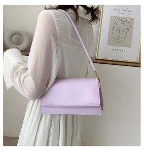 Detail of lavender PU leather shoulder bag with gold hardware worn by a model