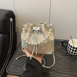 Blue embroidery bucket bag with pearl handle and golden chain strap in life scene