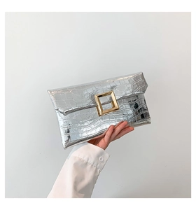 Close-up of silver crocodile pattern envelope clutch featuring a large gold square buckle