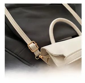 Close-up of adjustable golden buckle and metal hook on a white PU leather handbag