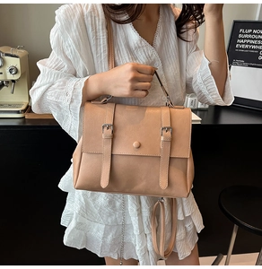 Détail du sac de postier marron vintage de style collège tenu par un mannequin élégant