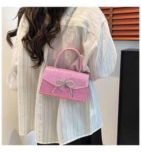 Detail of pink sequin shoulder bag with rhinestone bow and silver chain on model