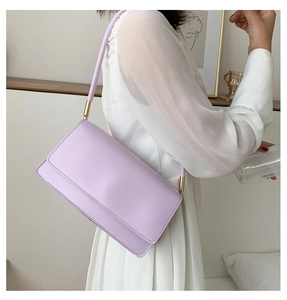 Close-up of light purple leather shoulder bag with gold cylindrical metal hardware detail
