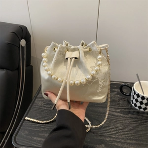 Elegant off-white embroidered bucket bag with pearl handle and golden chain strap
