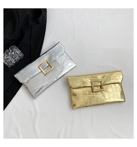 Detail view of gold and silver crocodile textured clutch bags with square metal buckles
