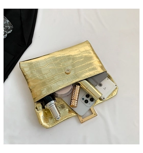 Detail of gold faux crocodile texture envelope clutch bag with magnetic snap closure