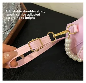 Detail der rosa Ledertasche mit verstellbarem Gurt, Goldbeschlag und Perlengriff