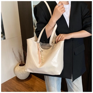 Detail of white glossy tote bag showing embossed brand logo and premium patent leather