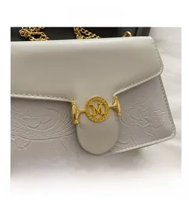 Detail of white leather shoulder bag with floral embossing and gold M-buckle