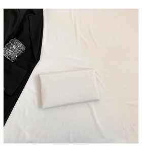Detailed view of white crocodile pattern envelope clutch with textured faux leather