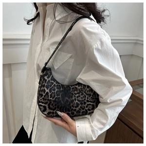 Gros plan du sac baguette léopard sur un mannequin en chemise blanche, décor minimaliste
