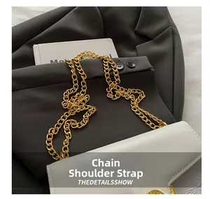 Close-up of white leather handbag featuring a gold Medusa relief buckle and chain strap