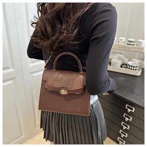 Close-up of a vintage dark brown leather handbag featuring a golden metallic twist lock