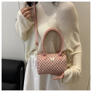 Detail of pink cylinder bag with butterfly decor and adjustable strap on model