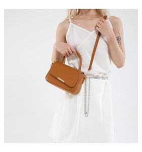 Bolso de mano de cuero marrón con herrajes dorados y correa mostrado en una modelo