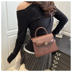 Detailed view of the brown leather crossbody bag with a metal twist lock and strap