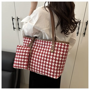 Detailed view of red houndstooth tote bag and matching pouch with brown leather straps