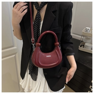 Dettaglio borsa a mezzaluna bordeaux con manico cilindrico e logo fashion stampato