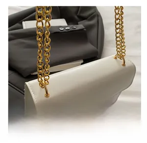 Detail of white baguette bag with gold chain strap and embossed texture finish