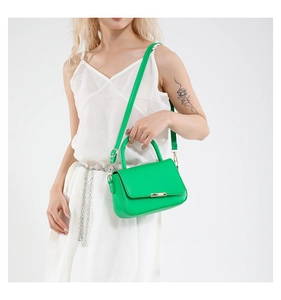 Bolso chic de cuero verde con hebilla dorada y correa ajustable mostrado en modelo