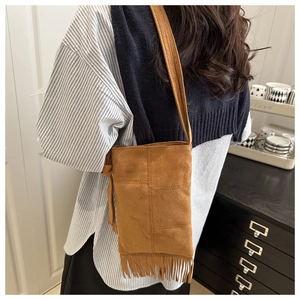 Macro detail of brown faux suede crossbody bag with long fringes in bohemian style