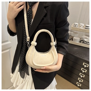 Dettaglio borsa a mezzaluna beige con manico a nodo decorativo e scritta fashion