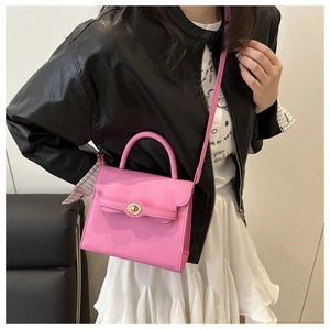 Detail of pink faux leather crossbody bag with golden clasp and matching shoulder strap