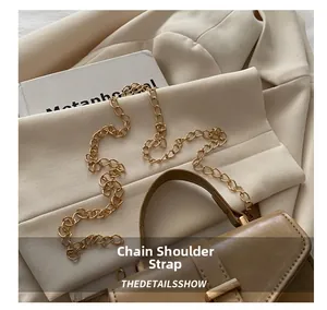 Detailed view of brown leather handbag with luxury gold metal chain strap on beige blazer