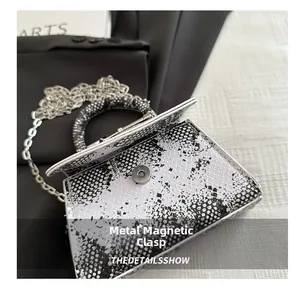 Detailansicht des Magnetverschlusses einer kleinen quadratischen Tasche mit Schlangenmuster