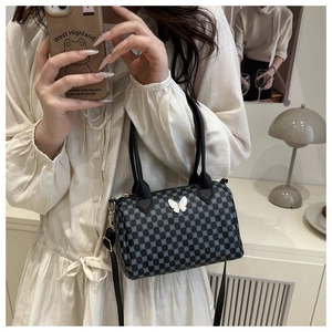 Detail of a vintage-style cylinder bag featuring blue geometric patterns and a white butterfly