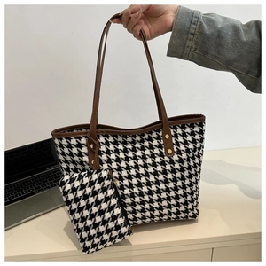 Detail of houndstooth tote bag with brown leather handles and matching small pouch