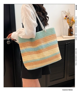 Vue latérale d'un grand sac fourre-tout tissé arc-en-ciel porté par un mannequin chic