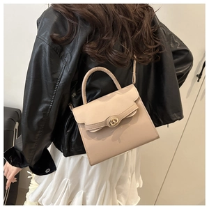Beige faux leather crossbody bag worn by a model with a gold-tone twist lock closure