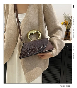 Close-up of dark brown crocodile pattern bag with unique gold metallic handle