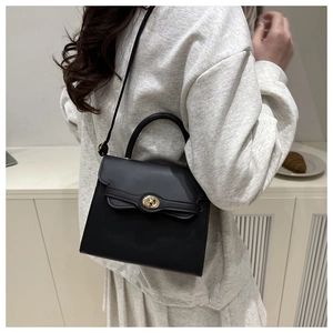 Classic black leather crossbody bag with gold metallic lock shown on a model