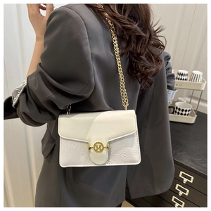 Detail showing the cream flap bag featuring floral texture and golden M letter buckle