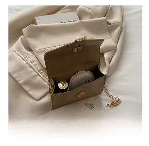 Detail showing internal capacity of khaki leather flap bag with gold chain and cosmetics