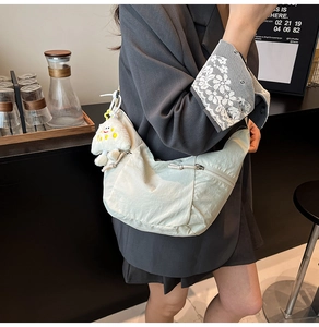 Close-up of lightweight nylon crescent bag with plush charm on stylish shoulder strap
