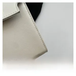 Close-up of beige leather handbag edge showing smooth matte texture and neat stitching