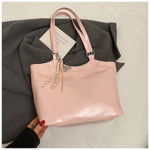 Detailed view of pink glossy tote bag with embossed lettering and striped tassel charm