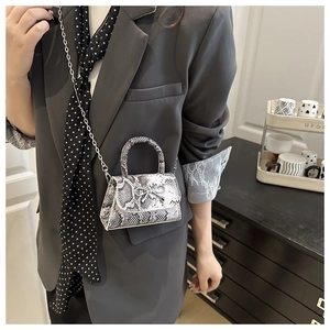 Detailed macro view of snakeskin pattern faux leather bag with silver bow accent