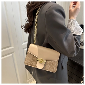Detail of vintage beige shoulder bag featuring floral embossing and gold chain strap