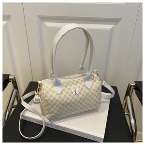 Detail of cylinder handbag featuring yellow circular patterns and a white metal bow clasp
