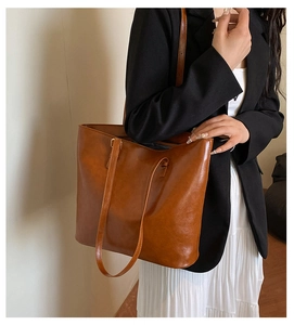 Close-up of brown vintage leather tote bag with glossy texture and shoulder straps