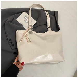 Detail of cream PU leather tote bag featuring debossed logo and woven lanyard decoration