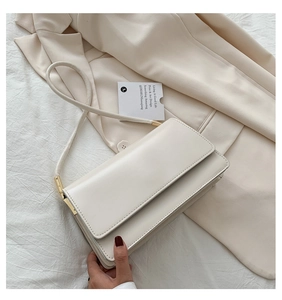 Detail of off-white rectangle shoulder bag with gold clasp and fine stitching