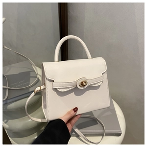 Detailed macro view of the cream white PU leather bag surface and gold rotating metal lock
